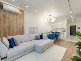Contemporary living room with stylish furniture, elegant chandelier, and open kitchenette.