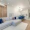 Contemporary living room with stylish furniture, elegant chandelier, and open kitchenette.