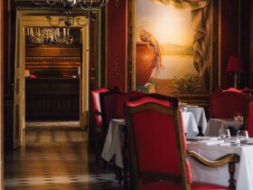 Luxurious dining room in a French restaurant with red chairs and chandeliers in Vonnas.
