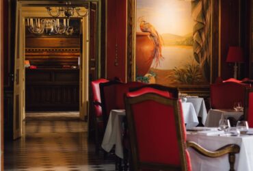 Luxurious dining room in a French restaurant with red chairs and chandeliers in Vonnas.