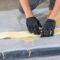 Technician wearing black gloves applying resin to a fiberglass pipe patch during a trenchless CIPP point repair installation.