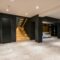 Modern interior with wooden staircase, black walls, and ample space, showcasing minimalistic design.