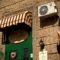 Restaurant awning over a green door with sign.