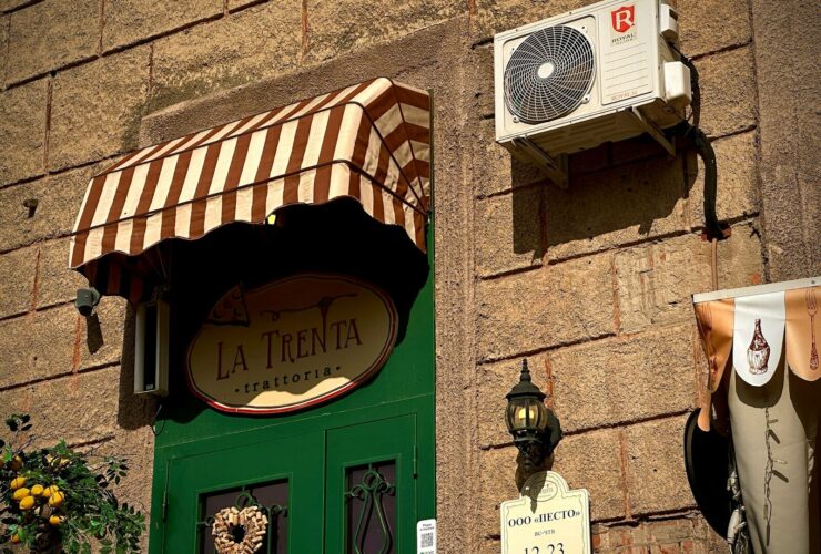 Restaurant awning over a green door with sign.