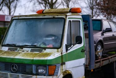 A green and white truck with a car on the back of it