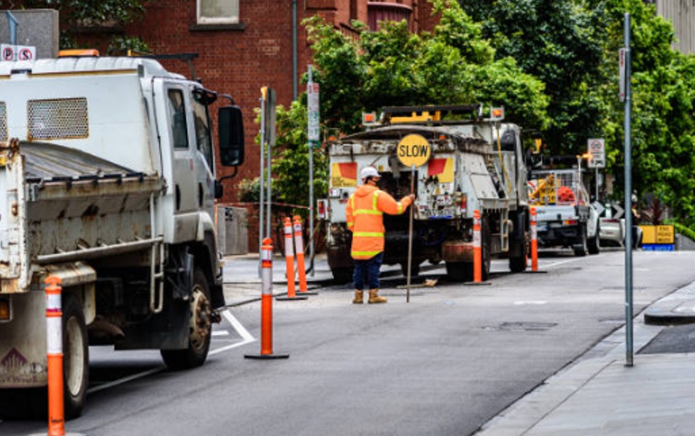 A Few Trucks Parked On The Side Of The Street And A Slow Sign. Construction Site Compliance