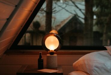 a bed sitting under a window next to a night stand