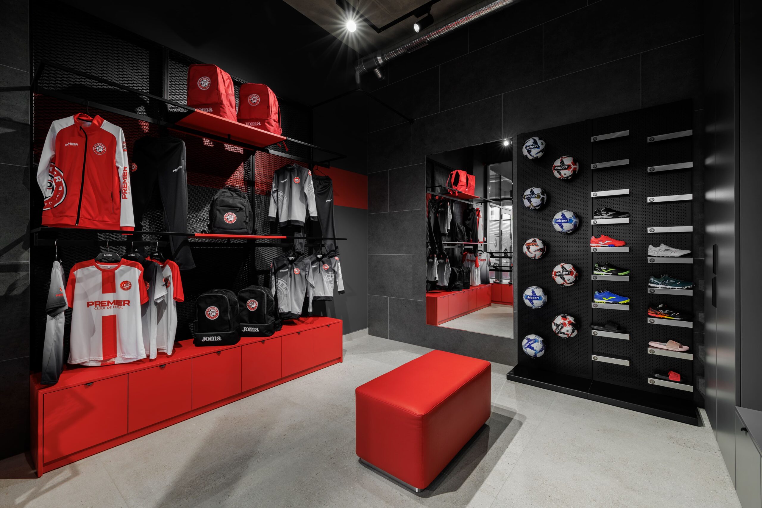 Interior of club shop with jerseys on red shelving and football boots display