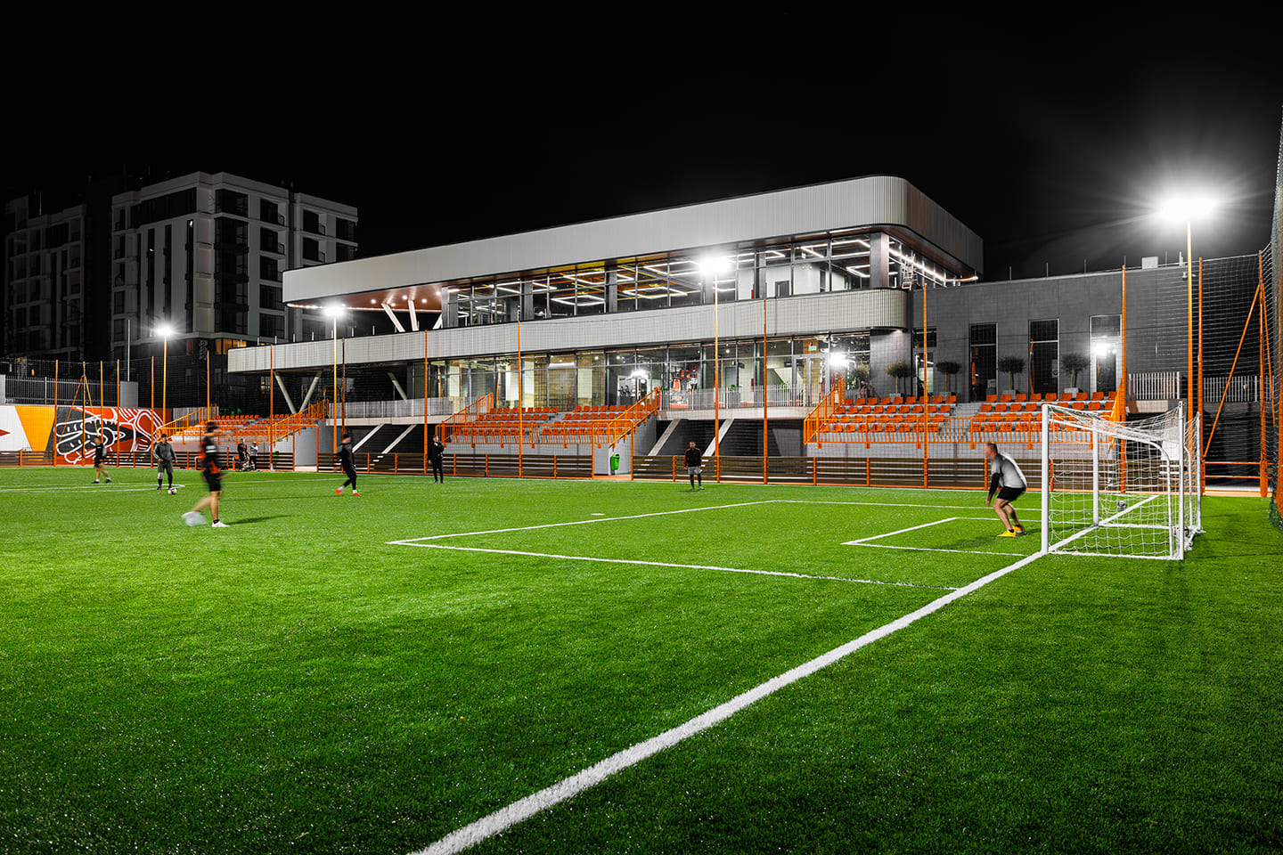 Night view of illuminated sports complex with players on field