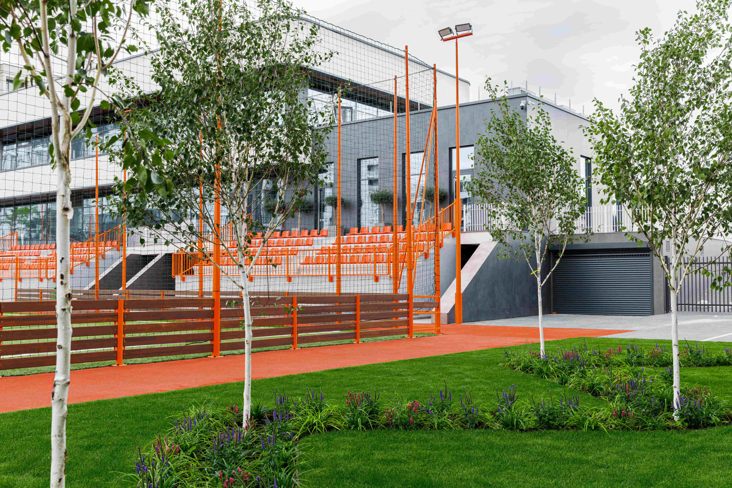 Exterior view through trees showing orange bleachers and building facade