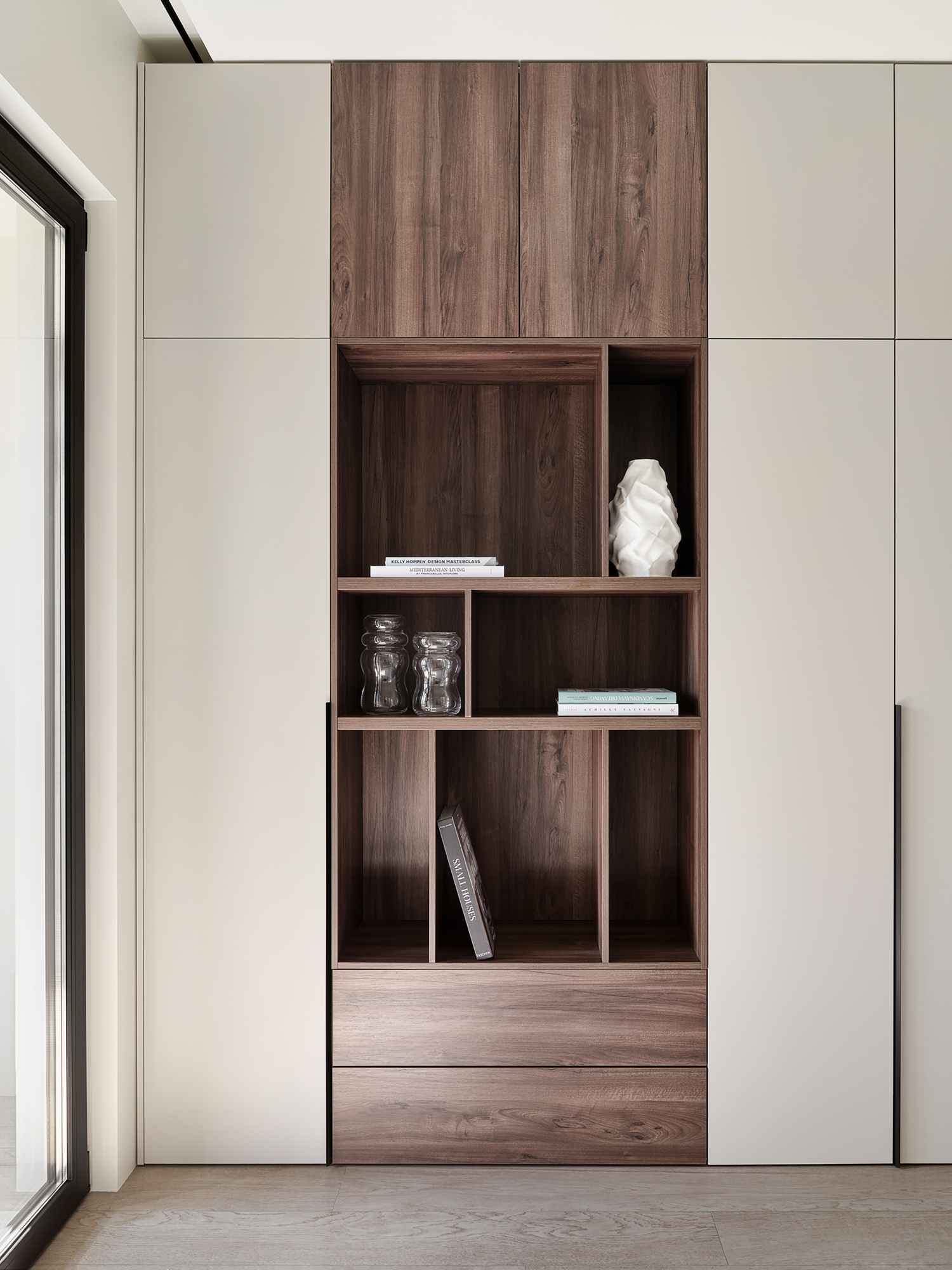 Floor-to-ceiling built-in storage unit with walnut open shelving and closed beige cabinets