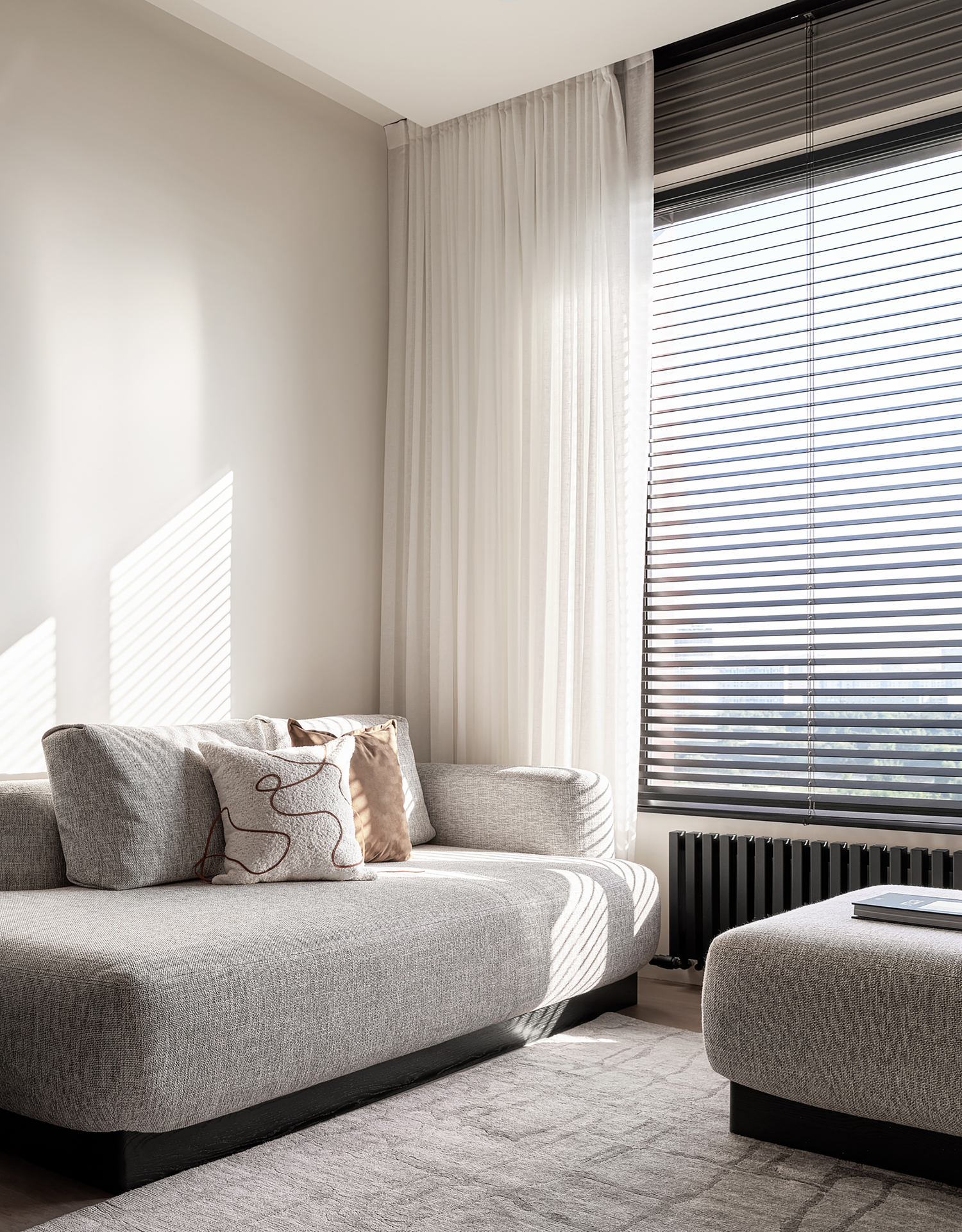 Grey fabric sofa with storage ottoman near window with bamboo blinds