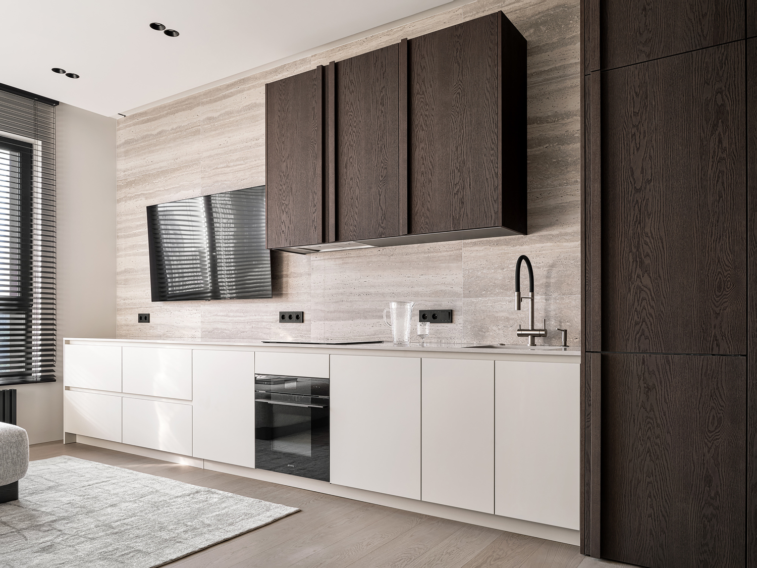 Kitchen with dark oak veneer upper cabinets and white lower cabinets against travertine backsplash