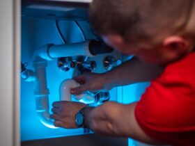 a man working on a pipe in a cabinet
