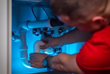 a man working on a pipe in a cabinet