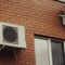 Air conditioners are attached to a brick building.