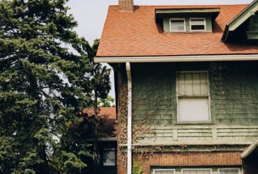 a house with a red roof and a tree in front of it