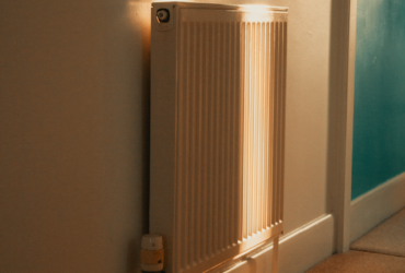 A wall-mounted radiator warmly lit by sunlight in a cozy indoor setting.
