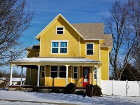a yellow house with snow on the ground