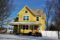 a yellow house with snow on the ground