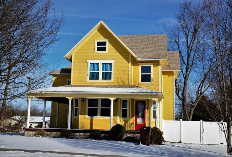 a yellow house with snow on the ground