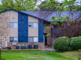Apartment building with stone, blue siding, and green lawn