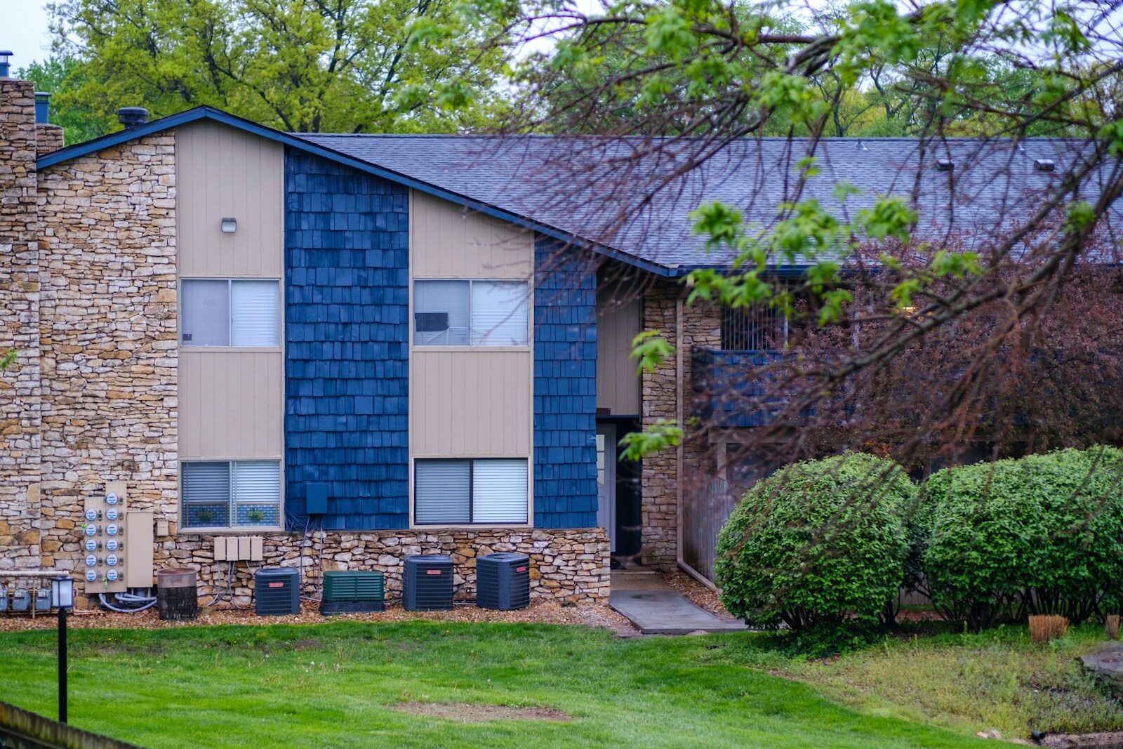 Apartment building with stone, blue siding, and green lawn