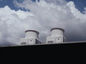 Two white devices on a rooftop against a cloudy sky