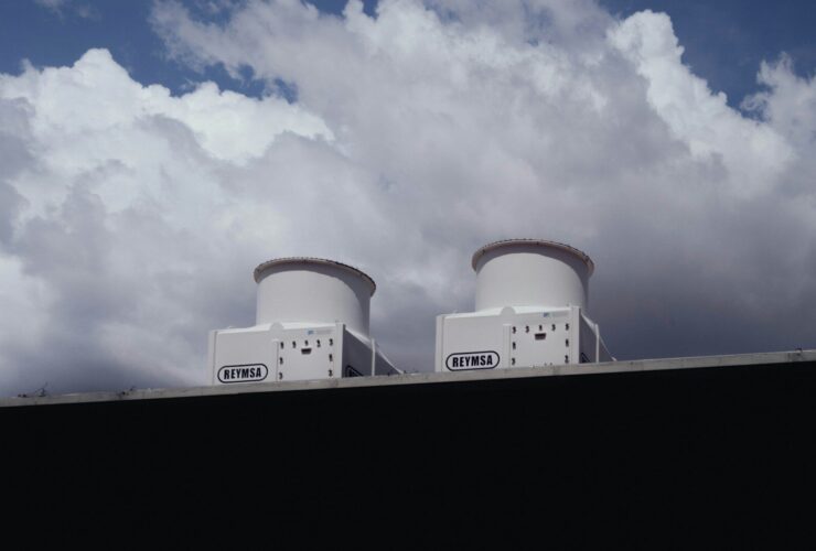 Two white devices on a rooftop against a cloudy sky