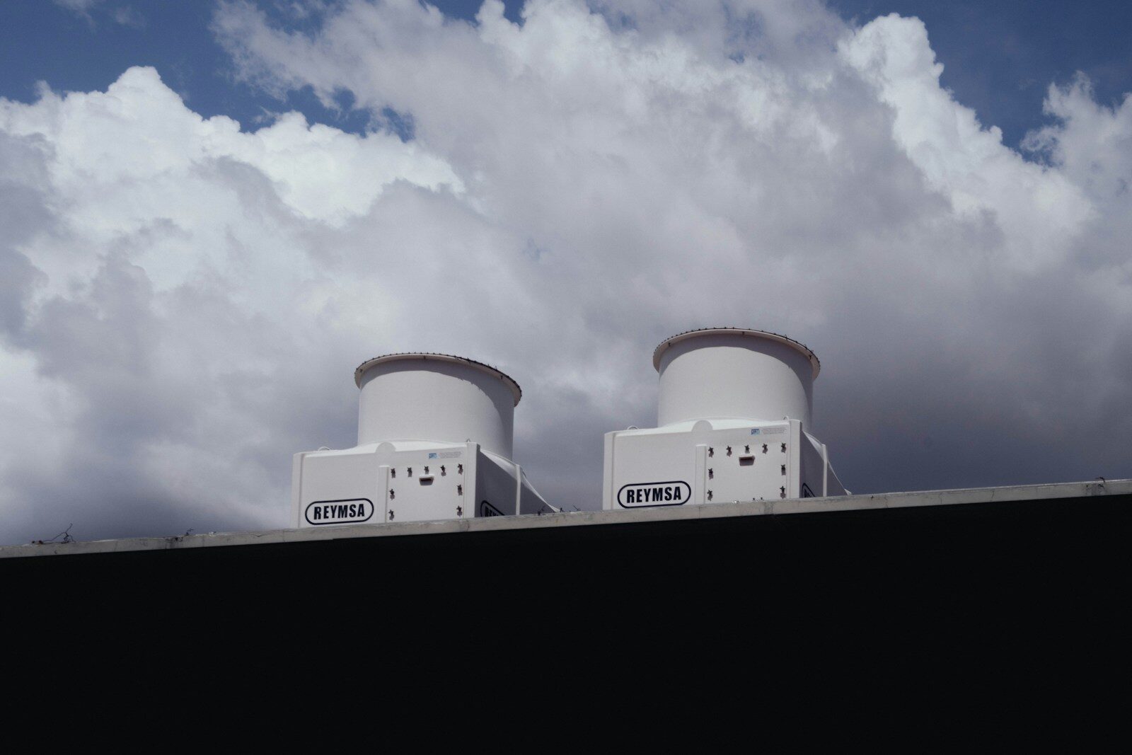 Two white devices on a rooftop against a cloudy sky