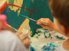 person holding paint brush painting on white and blue floral textile